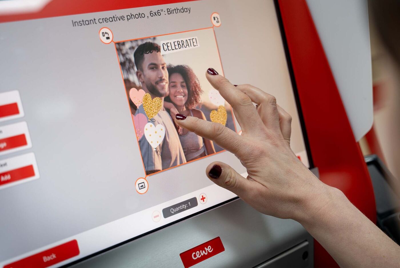 A person designs a creative photo for a birthday at a CEWE kiosk, with heart decorations on the screen.