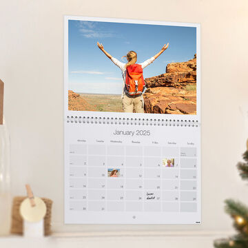 An open wall picture showing a calendar for January 2025 with a person looking happily into the distance, surrounded by nature.