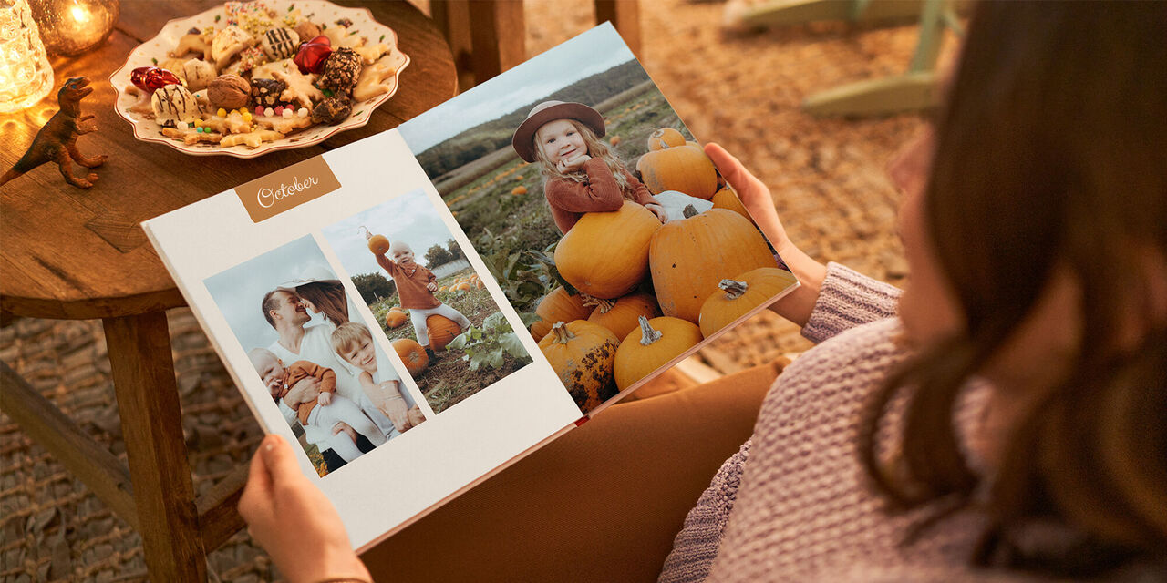 A CEWE PHOTOBOOK double page spread shows two pictures of the family in a pumpkin field under the title ‘October’.